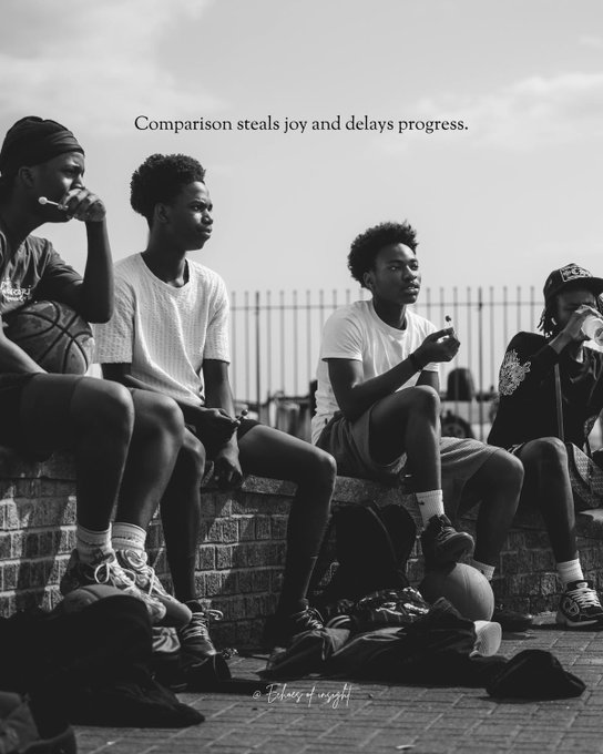A black-and-white photograph of four young men sitting on a brick wall, with the overlay text 'Comparison steals joy and delays progress.' and a small signature at the bottom.