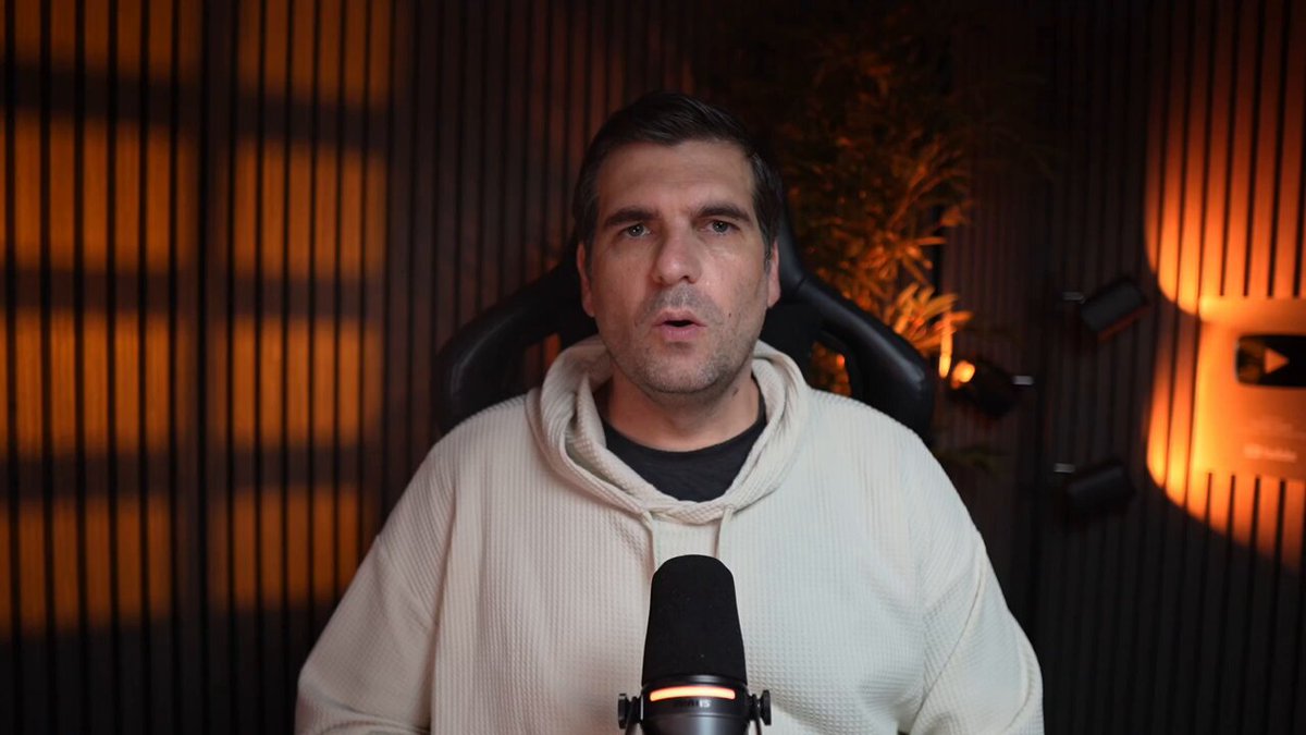 The image depicts a man wearing a white sweatshirt standing inside of a room equipped with a microphone, possibly suggesting he is recording or broadcasting something related to the Wall Street move and corporate crypto adoption by T. Rowe Price.