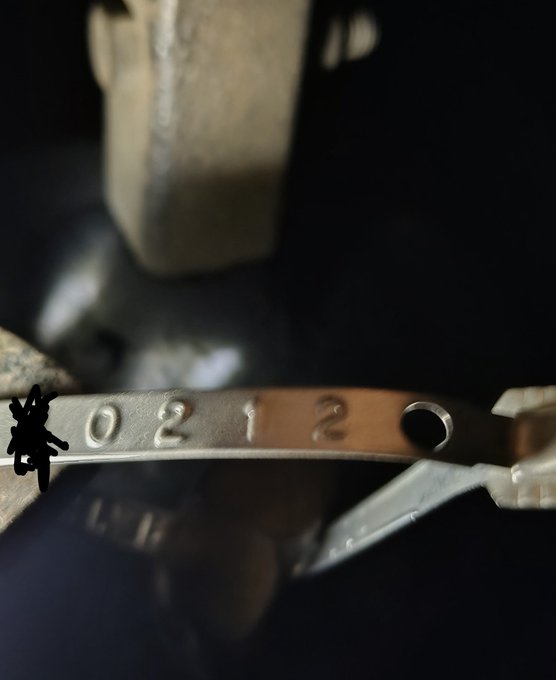 A metal cuff bracelet stamped with "0212" is held against a black Cro/CSGO wrist accessory, likely representing NFT #0212 from the Cronos/CroArmy collection. The visible text aligns with the post's reference to "#212" and "CroArmy," symbolizing the community's commitment to HODLing despite setbacks.