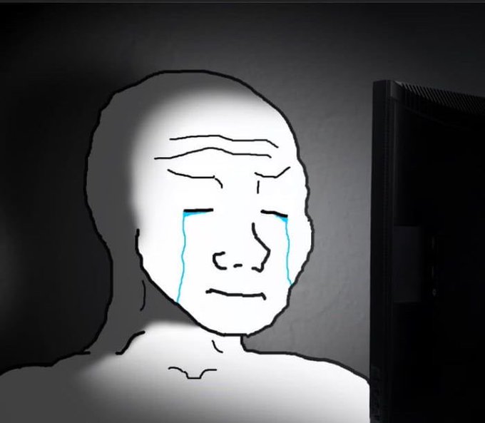 A sad Wojak face character with cartoon blue tears streaming down his cheeks sits in front of a computer monitor in a dark room, illustrating the crypto meme of an investor who bought a coin expecting 100x gains only to be left holding an empty community token.