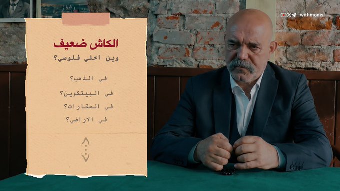 A serious-looking bald man with a mustache sits at a table beside a graphic titled "الكاش ضعيف" (Cash is weak), listing questions about gold vs. Bitcoin. The image ties to the post's theme of building wealth from nothing, with the "weak cash" graphic setting up the video's discussion about Bitcoin as a stronger alternative.