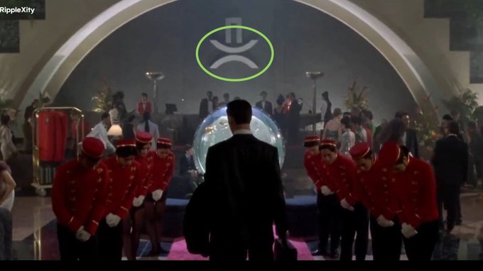 A man in a suit stands before a giant XRP logo as two lines of uniformed staff bow to him, echoing the iconic scene from "The Matrix" where the character Neo is presented as "The One." The image visually reinforces the post's claim that "XRP is the chosen one" by depicting the Ripple logo in place of Neo's grand, almost messianic arrival.