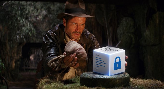 A man in a fedora and leather jacket (resembling Indiana Jones) reaches out toward a glowing white cube labeled 'Chain Link' with a padlock icon, set in a dark cave setting.