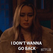 The image features a woman with blonde hair wearing a brown coat sitting down. The caption reads "I DON'T WANTNA GO BACK netflix", which seems to be a reference to a popular streaming platform like Netflix, where people often watch movies or TV shows for entertainment purposes.