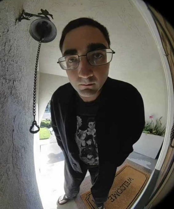 A young man wearing glasses and a black graphic sweatshirt is captured in a fisheye lens selfie standing on a "WELCOME" doormat at his front door. The fisheye perspective and his hunched, wide-eyed expression humorously mirror the post's message about searching through the "trenches" of Solana cryptocurrency projects hunting for a 100x return.