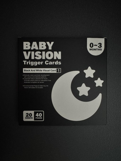 A black box of 'BABY VISION Trigger Cards' for infants aged 0-3 months, featuring black and white visual cards with a moon and stars design, containing 20 sheets/40 pages.