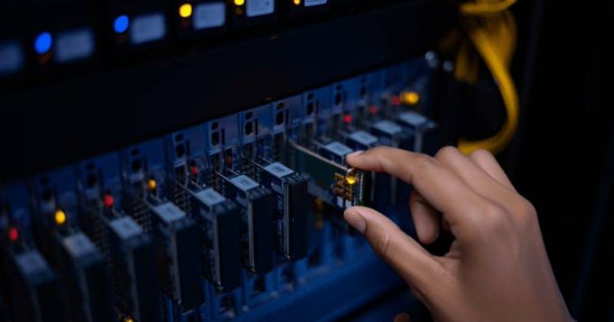 A hand inserts a memory module into a circuit board in a server rack, illustrating the technological infrastructure behind the record-breaking debut of the $RAM leveraged crypto ETF. The image evokes the underlying computing power and storage systems essential to the booming cryptocurrency trading market.