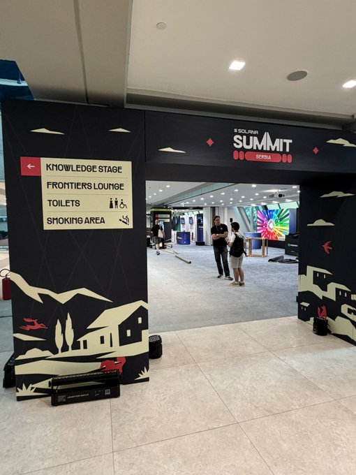 An entrance to the 'SOLANA SUMMIT BERLIN' event with a sign indicating directions to the Knowledge Stage, Frontiers Lounge, Toilets, and Smoking Area.