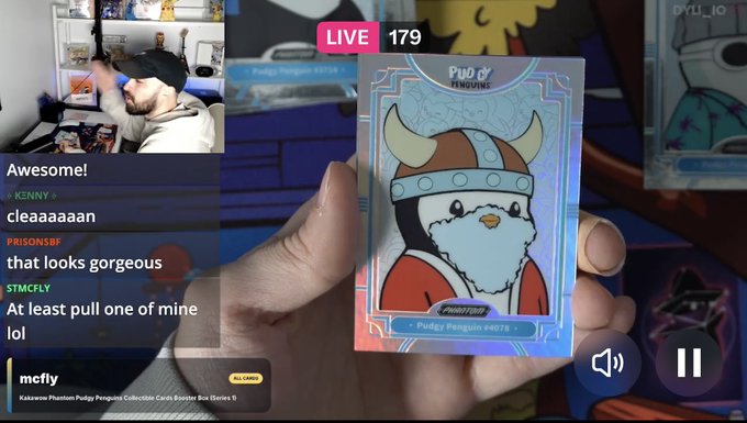 A livestream screenshot showing a hand holding a holographic Pokemon trading card of Pudgey Penguin, with viewer comments like 'Awesome!' and 'cleaaaaan' visible alongside a streamer wearing a cap.