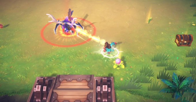 A top-down view of a video game battle on a grassy field, where a character fires a beam at a winged, glowing enemy creature near a treasure chest and a wooden gate.