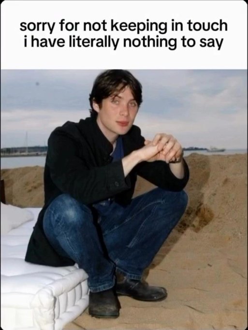 A person with shaggy dark hair sits on a mattress on a sandy beach, wearing a black coat and jeans, with the caption "sorry for not keeping in touch i have literally nothing to say" above them. The image captures the relatable mood of struggling to maintain friendships due to having nothing interesting to share, matching the post's sentiment.