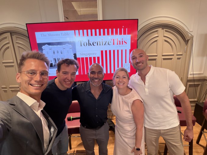 The image shows five RedStone partners (including Raj Arikam, Reid, Heintsight, and Kristen from FTST) smiling together in front of a presentation screen displaying "The Mason's Table Singapore" and "TokenizeThis" at what appears to be a networking event.