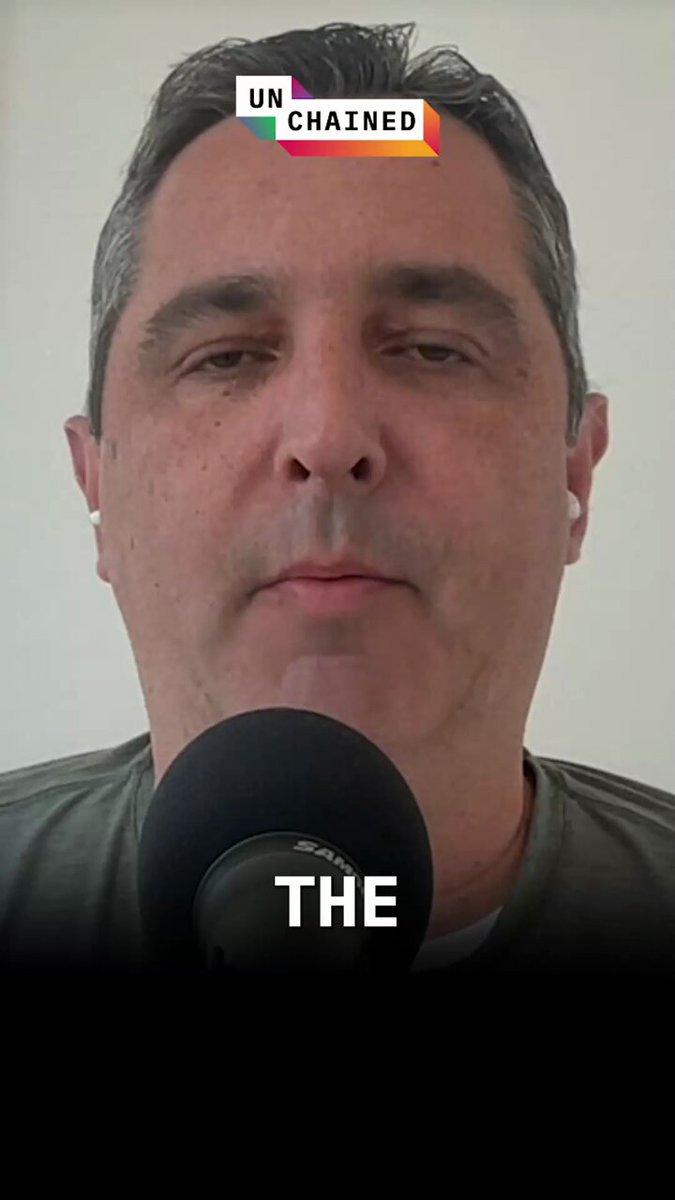 The image features a man wearing a grey shirt, standing next to a microphone with a caption that reads "The". The caption also includes some text about Bitcoin sales and market premium pricing strategies.