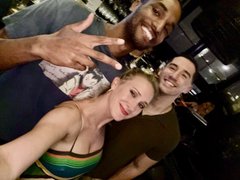 A slightly blurry selfie of three smiling young people posing together, with one person making a peace sign.