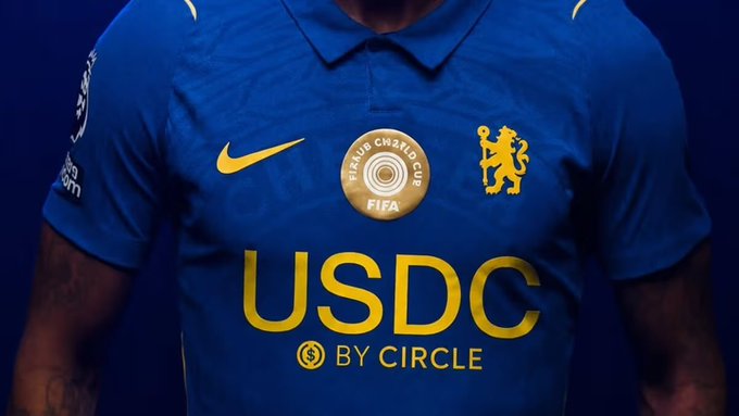 A close-up of a blue Chelsea Football Club jersey featuring the Nike swoosh, Chelsea crest, a 'SINGAPORE CRYSTAL CUP FIFA' badge, and 'USDC BY CIRCLE' sponsor text.