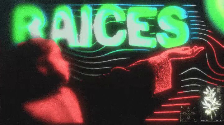 "RAICES" written in green neon letters, with a person's hand reaching out towards it.
