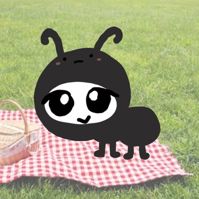 A cartoon-style black character with antennae, big eyes, and a small smile drawn over a photograph of a red and white checkered picnic blanket on grass next to a wicker basket.