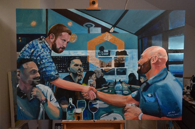 A painted artwork on an easel depicting men in a restaurant, with one man reaching across the table to shake hands with a bald bearded man holding a wine glass.