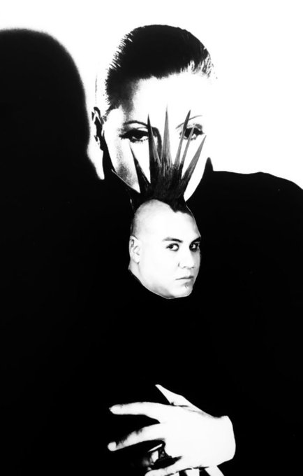 A surreal, high-contrast black-and-white image showing a person with a mohawk whose head is formed from or merging with another face below, with a hand visible at the bottom.