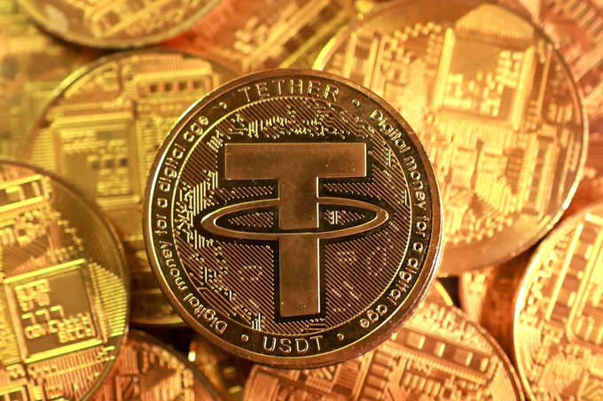 The image features a close-up view of a coin with the word "Tether" written on it. The coin appears to be made of metal and is shiny due to its gold color. It has a unique design, which includes a ring around the center of the coin. The coin also has some text that reads "XAUT (Tether Gold)". This suggests that the coin may have been minted as part of a new cryptocurrency called Tether Gold or a similar digital token. The image is accompanied by a caption that provides information about the coin and its purpose, which is to serve as a store of value in the form of digital tokens.