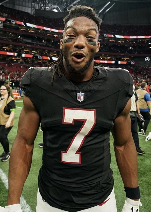 Atlanta Falcons player Bijan Robinson, wearing jersey number 7, stands on the field after a game with eye black on his cheeks.