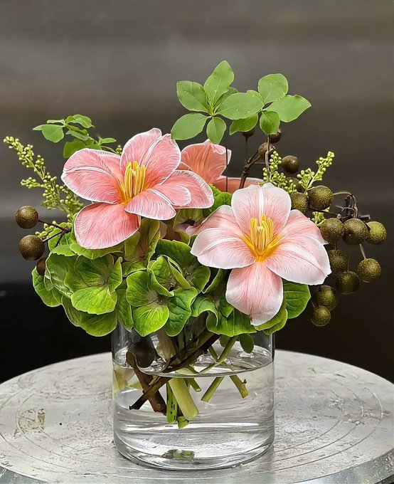 A bouquet of pink flowers and green berries sits in a clear glass vase, symbolizing fresh beginnings and new opportunities. The arrangement's vibrant blooms and lush greenery mirror the post's message of stepping into a new chapter with energy, luck, and perseverance.
