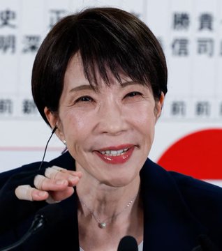 A Japanese woman with short dark hair, wearing a navy blazer and pearl necklace, smiles while speaking into a microphone at a press conference with Japanese text on the backdrop behind her.

The image appears unrelated to the post's claims about XRP and a "New World Order," showing instead what looks like a routine Japanese press event featuring an official, with no visible connection to cryptocurrency or financial messaging.