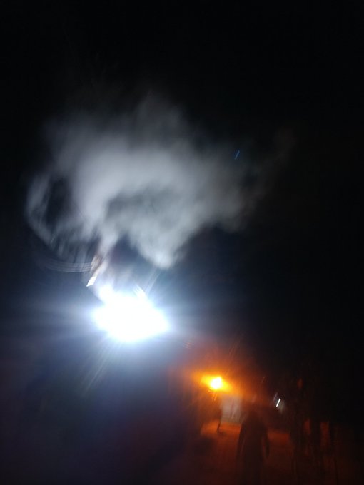 A blurry night scene shows bright lights and what appears to be smoke or fog in the dark sky, with silhouetted figures visible at the bottom near an orange-lit area. The image seems to loosely represent the "good night" theme of the post, though it has no direct connection to the wellness app or $SLEEP token being promoted.