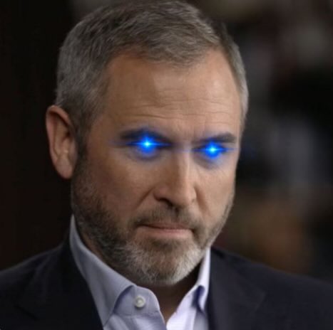 A close-up photo of a man with short graying hair and a beard, wearing a blue shirt and dark jacket, with glowing blue eyes added as a digital effect.