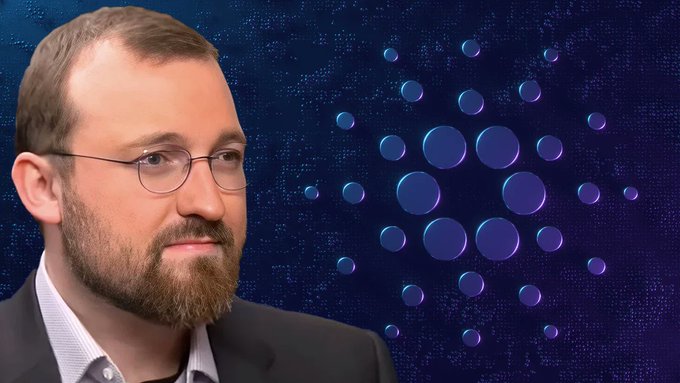 The image features a man wearing glasses with a beard, standing against a blue background that has circles on it. The caption below the image reads "HUGE: HOSKINSON WARNS OF CARDANO DEFI SHUTDOWNS IN H2 2026 Charles Hoskinson says more Cardano DeFi apps could close in the second half of 2026, citing funding, governance, and commercialization problems".