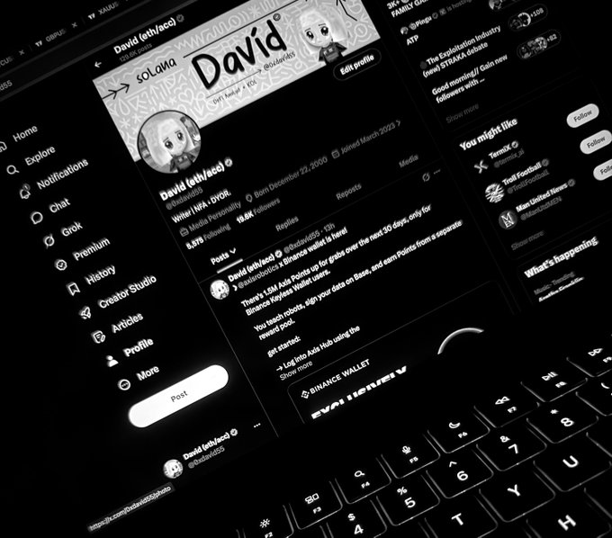A black and white photo showing a computer monitor displaying a Twitter/X profile for 'David (eth/vacc)' with 18.6K followers, positioned above a laptop keyboard.