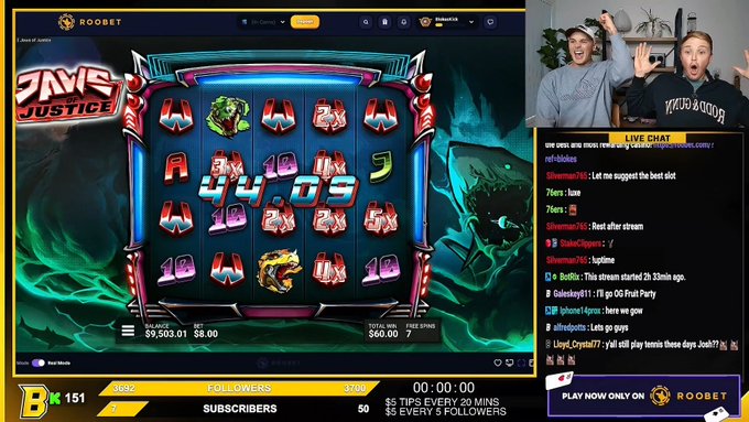 A live Twitch stream screenshot of a slot game called 'Time Justice' on ROOBET, featuring two streamers in a webcam overlay, a live chat, and a $9,503.01 balance.