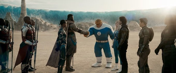 A promotional image from The Fantastic 4: First Steps showing the team in their blue and white uniforms standing in a desert landscape with a CGI wave rising behind them.
