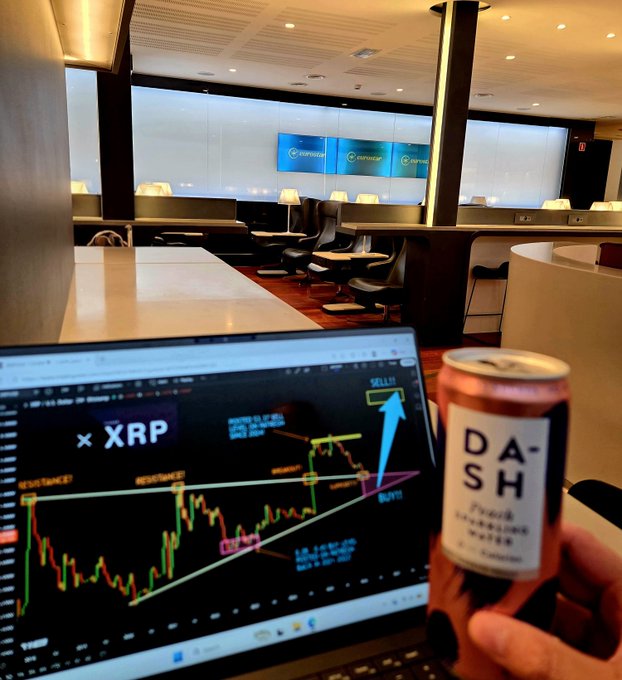 A person holds a can labeled "DASH" while their laptop displays an XRP trading chart marked with "RESISTANCE," "BULLS," "BUY!!," and "SELL!!" signals, set inside an empty "EXPERIENCE" lounge. The image captures the post's blend of luxury lifestyle and crypto trading, showing the trader enjoying a private first-class lounge while sharing XRP take-profit chart analysis.