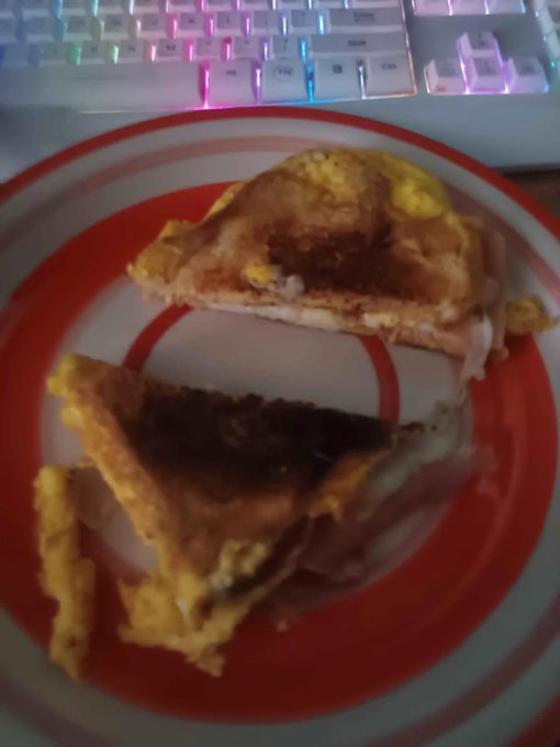 A grilled sandwich cut in half, served on a red and white striped plate in front of an RGB-lit keyboard. The meal complements the post's message about staying productive during slow market periods—analogous to taking time to refuel and refocus while waiting for better opportunities to enter the market.