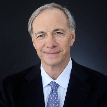 Ray Dalio, founder of Bridgewater Associates, smiling in a professional portrait wearing a dark suit and patterned tie. The image accompanies his bullish recommendation to sell bonds and allocate 10-15% of portfolios to gold and Bitcoin amid warnings of an impending U.S. debt crisis.