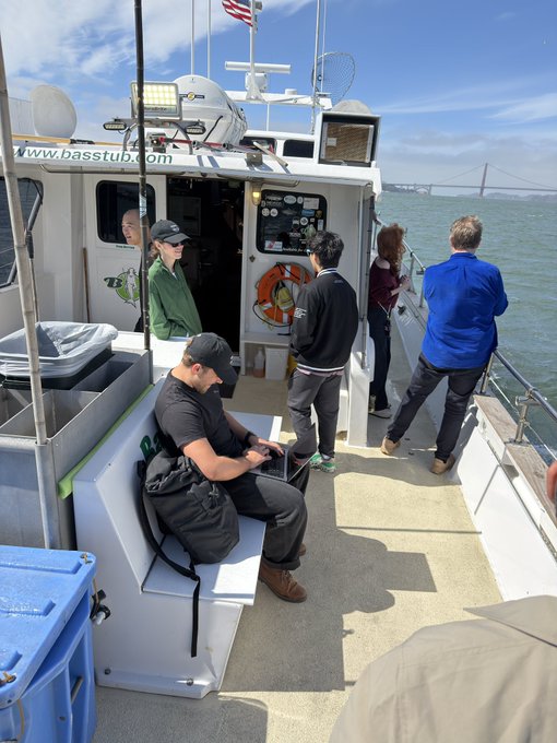 Passengers enjoy a boat tour aboard a vessel labeled "www.basstup.com," with the Golden Gate Bridge visible in the background as they take in the scenic views from the deck.