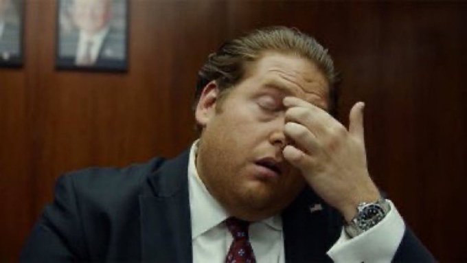 A man in a suit and tie pinches the bridge of his nose with his eyes closed, conveying a look of exasperation or fatigue as he reacts to the post referencing "bitcoin cash?"—his expression humorously capturing the weariness of someone exhausted by yet another cryptocurrency discussion.