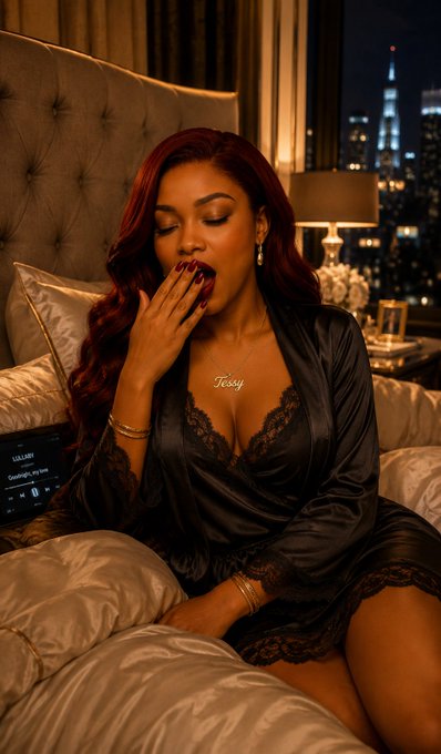 A woman with red hair wearing a black lace-trimmed robe sits on a bed, touching her lips while wearing a 'Teddy' name necklace in a dimly lit room with a city view.