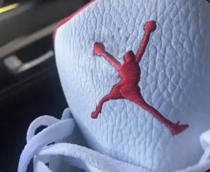 A close-up of the Jumpman logo on the tongue tag of a white sneaker, with the iconic silhouette appearing to have an extra leg.