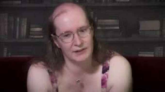 In the image, a woman with long hair wearing glasses sits on a couch against a backdrop of bookshelves filled with various books. The woman appears to be engaged in conversation or posing for a photo. The caption at the bottom of the image reads "The cabal thanks you for playing $ZEC". This suggests that the woman might have been involved in a game, possibly related to the $ZEC currency, and is now receiving recognition from the cabal for her participation.