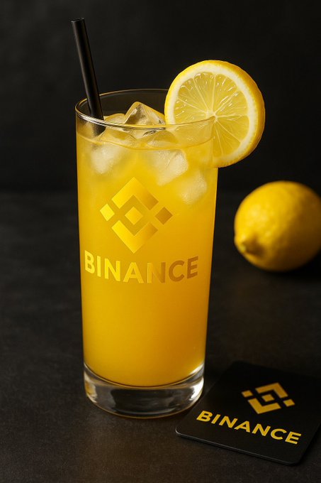 A tall glass filled with iced lemonade is garnished with a lemon slice and a black straw, featuring the "BINANCE" logo and its diamond emblem, with a matching Binance-branded card resting beside a whole lemon on a dark surface—visually pairing the message of "fresh ideas" and "fresh mindset" with a refreshing drink alongside the Binance brand name.