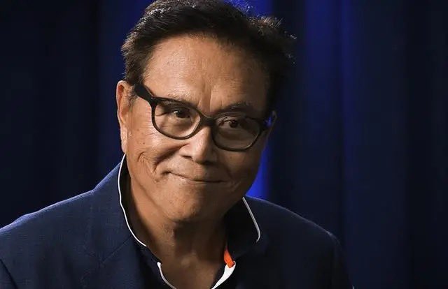 A man wearing glasses, a blue jacket, and smiling at the camera appears to be the main subject of a picture featuring him with his eyes focused directly onto the viewer. The photo seems to have been taken during an interview process where ethical questions are being discussed.