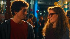 A young man with curly hair and a woman wearing glasses stand close together, looking at each other with slightly skeptical or knowing expressions, as if sharing an awkward secret—fitting the caption's joke about Sam Bankman-Fried's infamous involvement in crypto fraud.