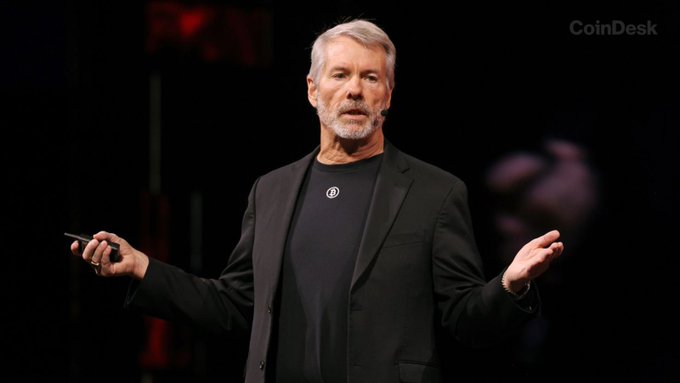 The image, from a CoinDesk-branded event, shows a gray-bearded man in a black blazer and t-shirt speaking on stage with a presentation clicker in hand, gesturing as he addresses an audience—visually conveying the reflective, accountable tone of the quote "mistakes were made in a wallet I controlled."