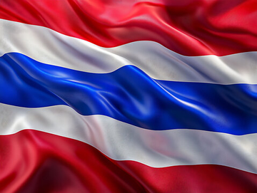 The image features a close-up view of a Thai flag, which has red, white, and blue stripes. The flag appears to be waving or blowing in the wind, creating a sense of movement and dynamism. The background of the image is blurred, drawing attention to the flag as the main focus.