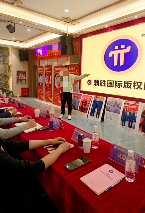 A presenter stands on stage at a Pi Network event in China, with a large screen displaying the Pi logo and Chinese characters "鼎胜国际版权" in the background, while attendees sit at red-draped tables with Pi-branded materials. The scene captures a corporate-style Pi Network meeting or announcement event in China, aligning with the post's celebration of Pi Network's growing presence there.