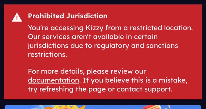 A red error screen displaying 'Prohibited Jurisdiction' with a warning that access to Kizzy from the current location is restricted due to regulatory and sanctions restrictions.