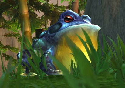 A blue and yellow frog-like character sits among grass and bamboo in a stylized 3D game environment.