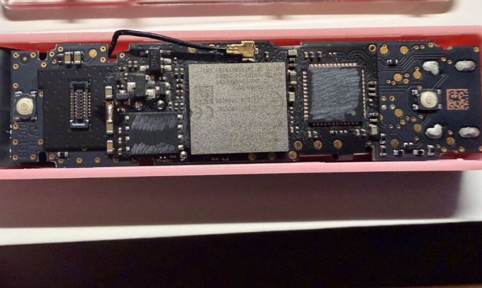 A close-up photograph of an exposed circuit board inside a red-cased device, showing various chips and components.